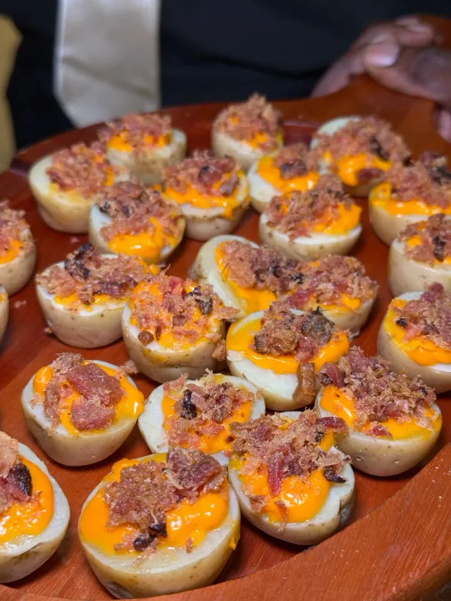 Mini batatas recheadas com cheddar cremoso e crispy de bacon crocante servidas em travessa de madeira