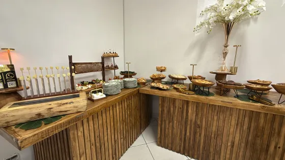 Buffet de brunch montado em balcão de madeira com bolos, pães e doces em suportes