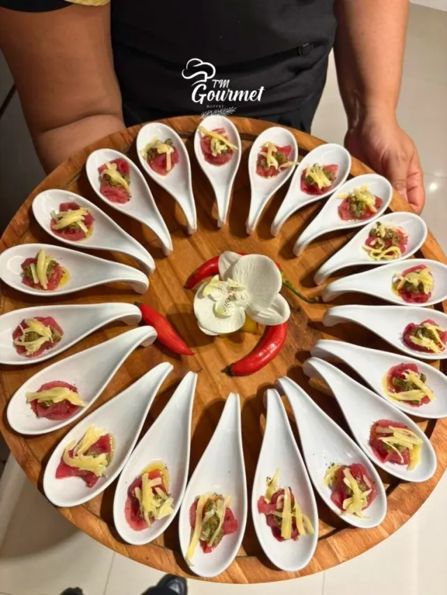 Bandeja redonda com colheres de entrada e orquídea no buffet TM Gourmet
