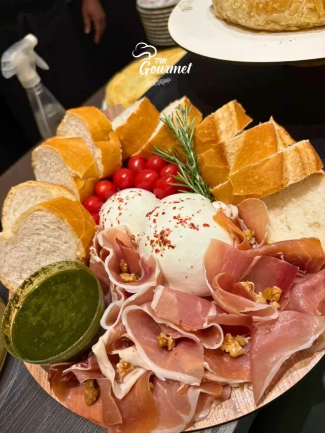 Tábua de entradas com queijo, presunto e pão no buffet TM Gourmet