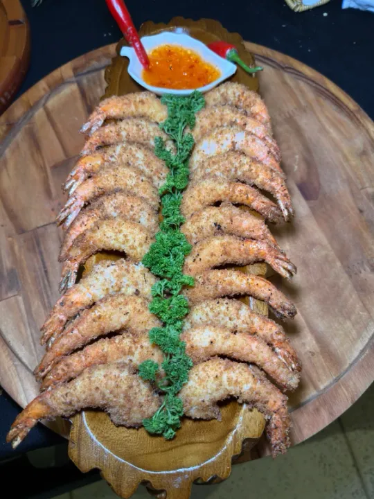 Travessa de camarões empanados com salsa e molho agridoce em tábua de madeira