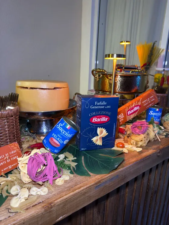 Estação de massas com massas artesanais, molho de tomate e roda de queijo parmesão