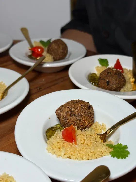 Pratos servidos com bolinho, cuscuz e tomate em mesa de festa