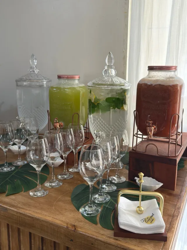Estação de bebidas com suqueiras de cristal, águas saborizadas com ervas, sucos naturais e taças